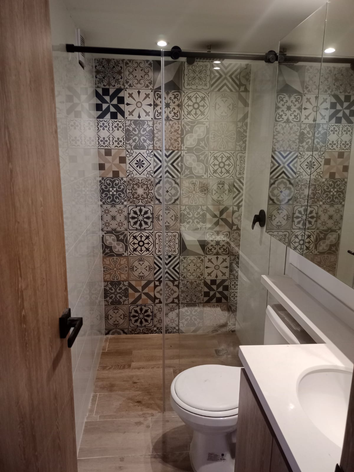 Baño remodelado con división de vidrio
